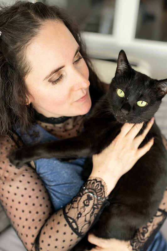 Eine Frau schaut liebevoll ihre schwarze Katze an, die sie auf dem Arm hält, während die Katze mit grünen Augen in die Kamera blickt – aufgenommen bei einem Hausbesuch in Luzern.